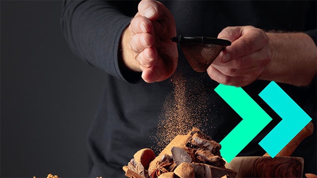 Man shaking spices onto a pile of ingredients.