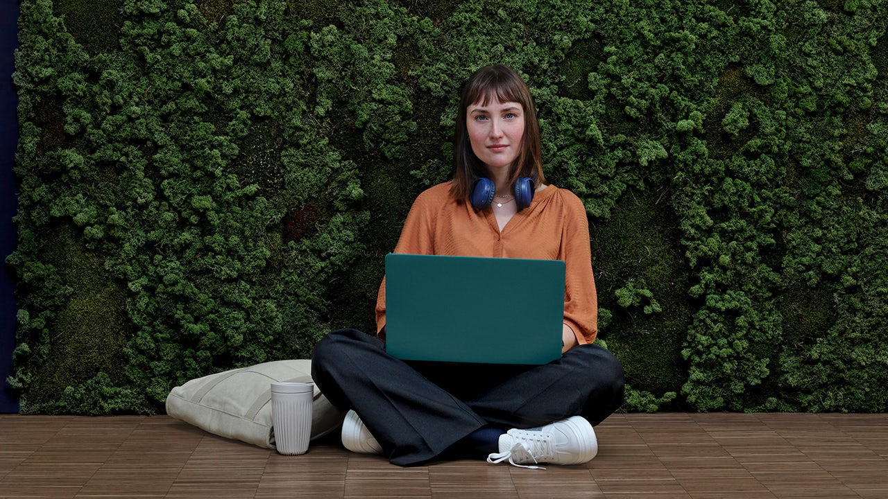A person is standing in front of a large screen displaying a colorful image of a rocket launch.