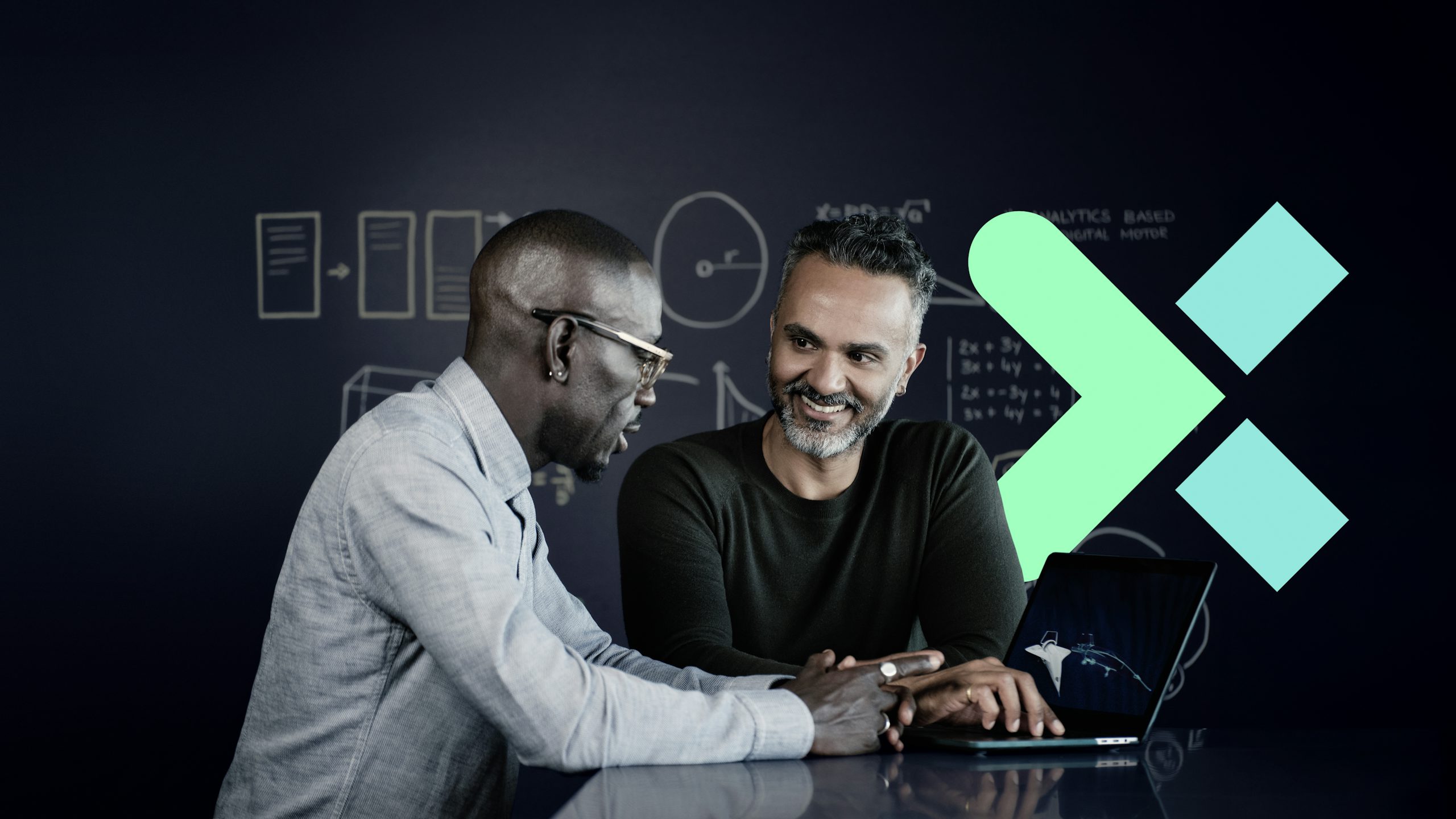 Two professional men collaborating on a laptop and smiling in front of a blackboard, a floating Xcelerator logo on the right.