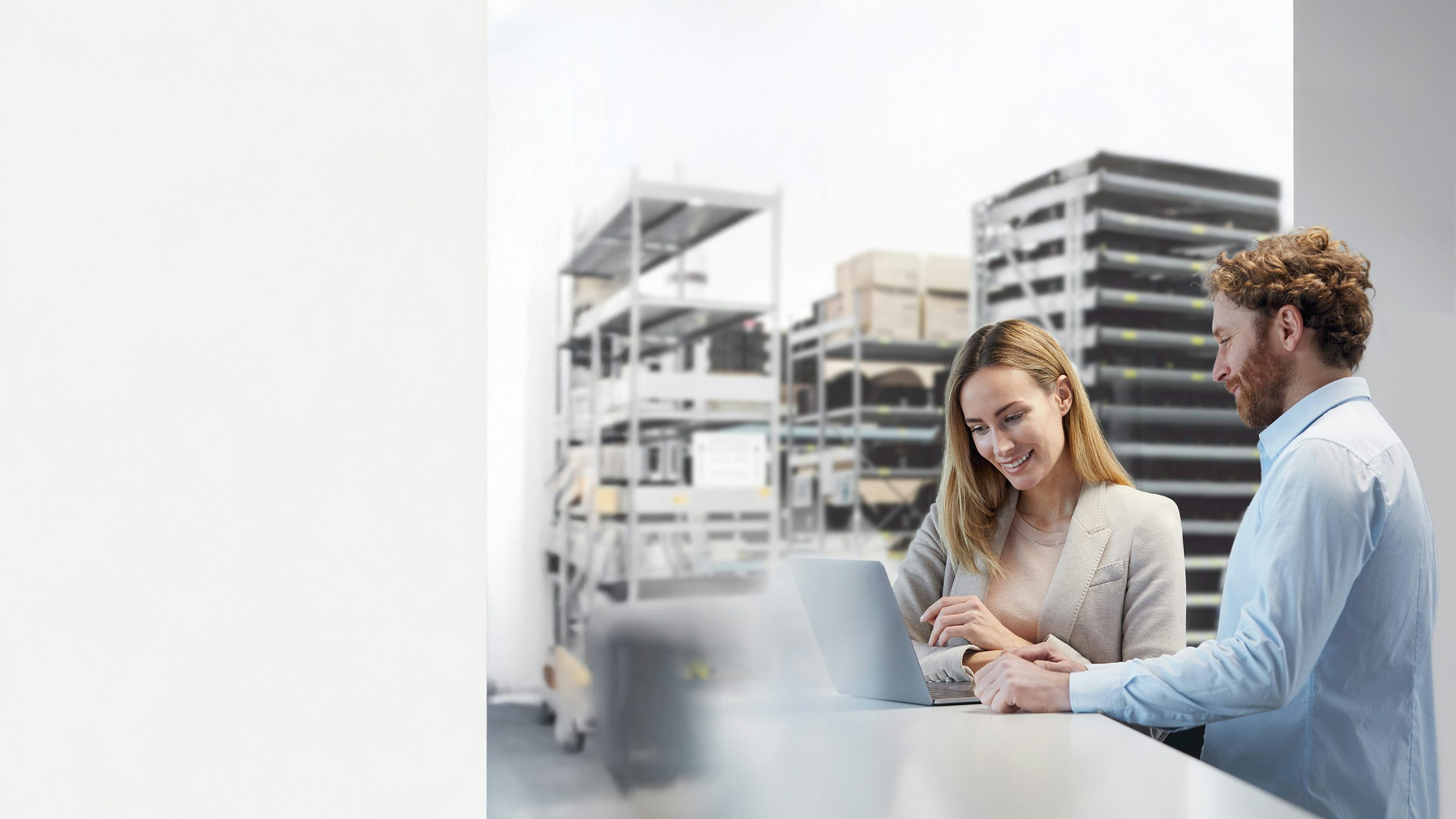 Woman and man standing at a desk in front of a laptop.