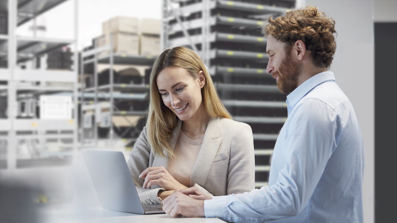 Man and woman standing in front of a laptop discussing something.