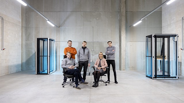 Five people gathered in a large data center.   