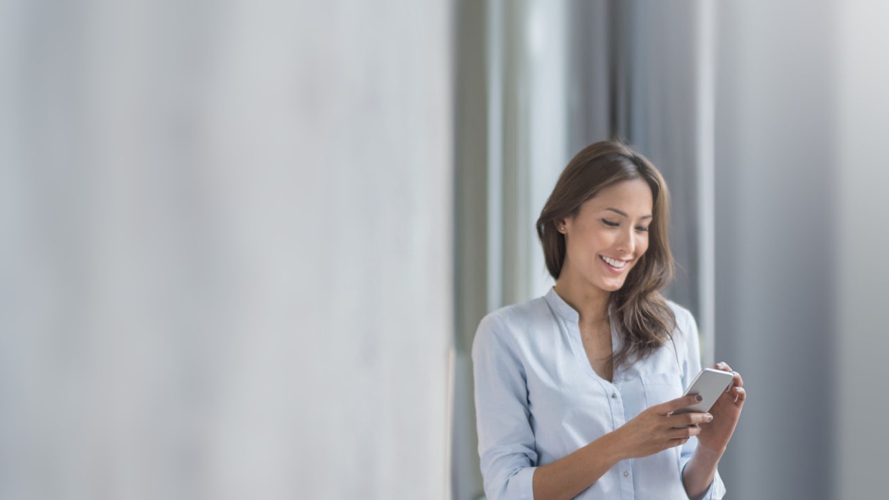A building owner looks at a smartphone in front of a building.