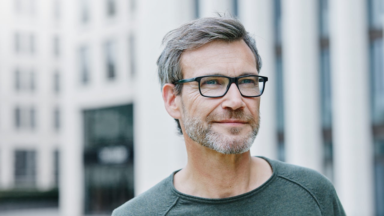 A system integrator in glasses stands in front of a building.
