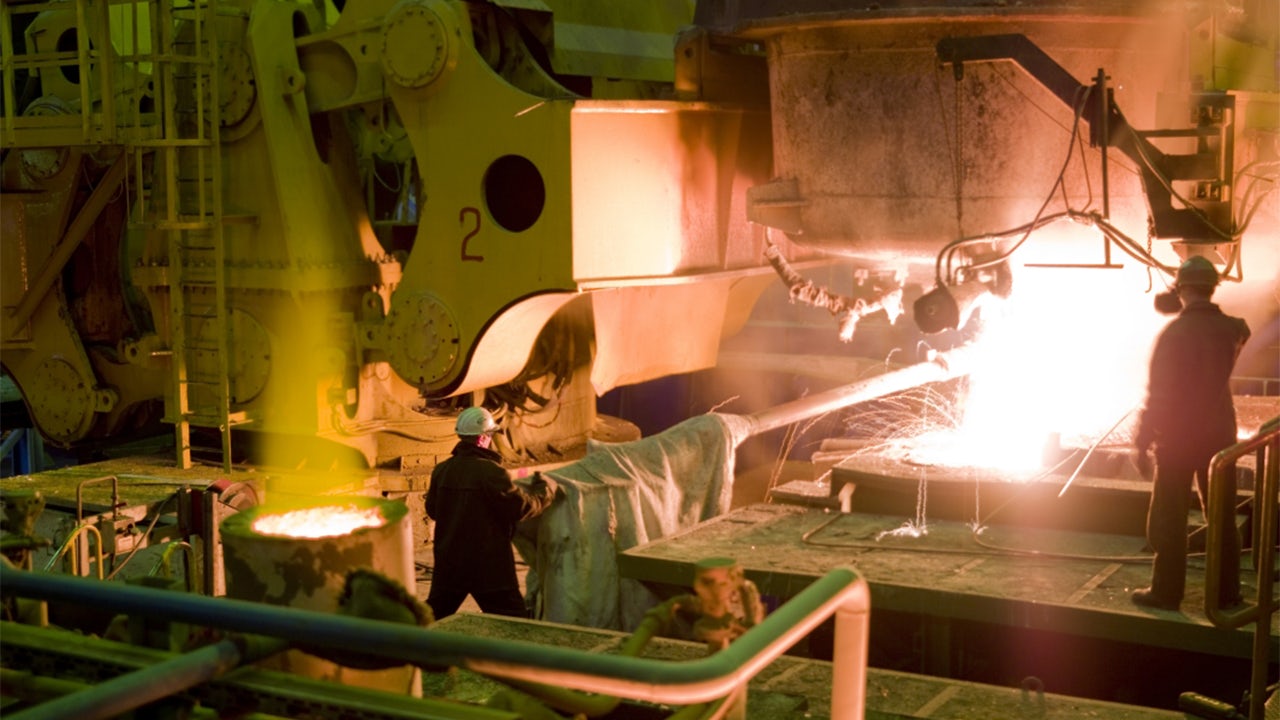 A man in a hard hat working in a steel manufacturing plant.