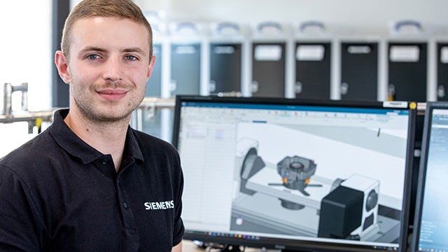 A person wearing a virtual reality headset interacts with holographic displays in an industrial setting.