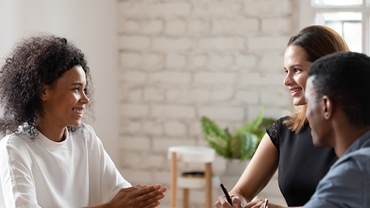 Conference room meeting between three people sitting at a table