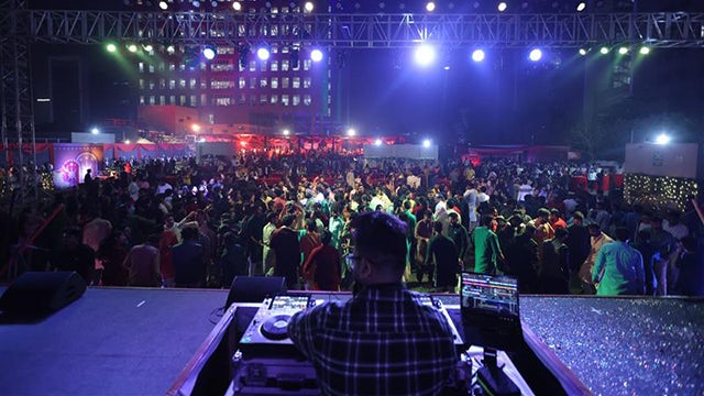 Diwali celebration with people lighting lamps and fireworks in the background.