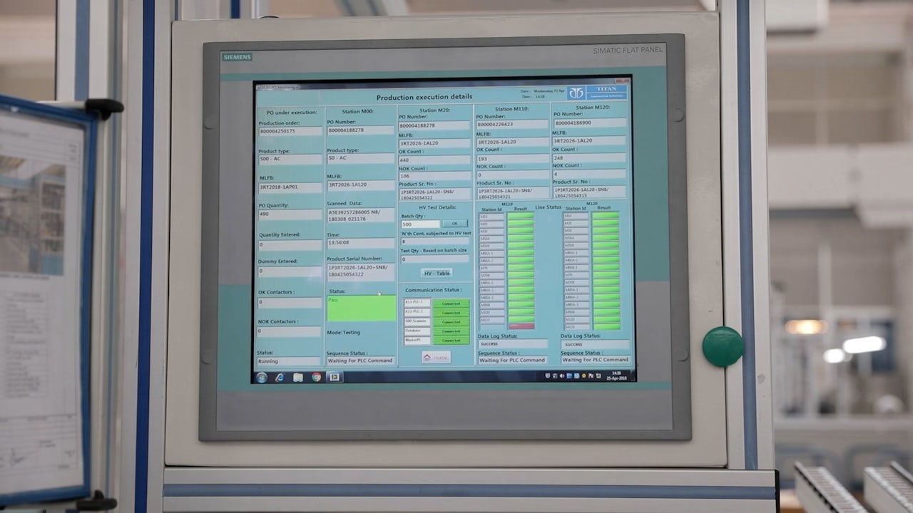 A person is standing in front of a white wall with a blurry background.