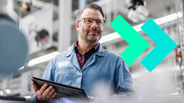 Worker in protective gear operating machinery in a factory setting with large metal equipment visible.