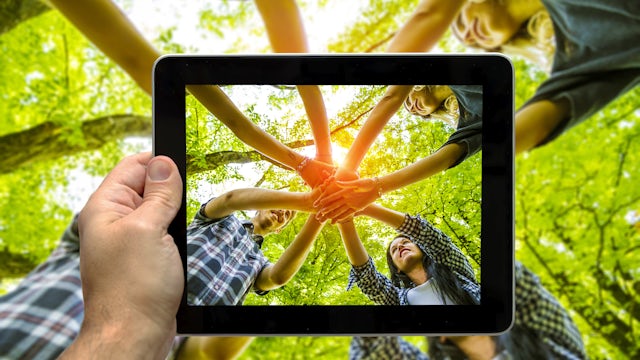 A person holds a sign about equalizing opportunities in front of a diverse crowd.