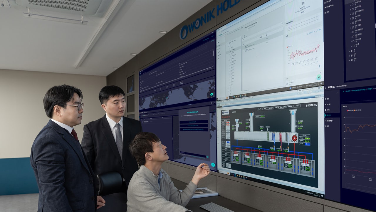Three WONIK HOLDINGS employees look at digital screen