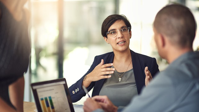 Woman explaining something to a group of people in a conference room.
