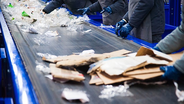Recycling plant workers sort waste materials on an assembly line
