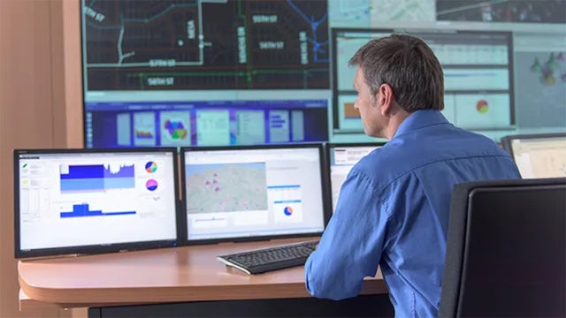 Man sitting in front of two computer monitors.