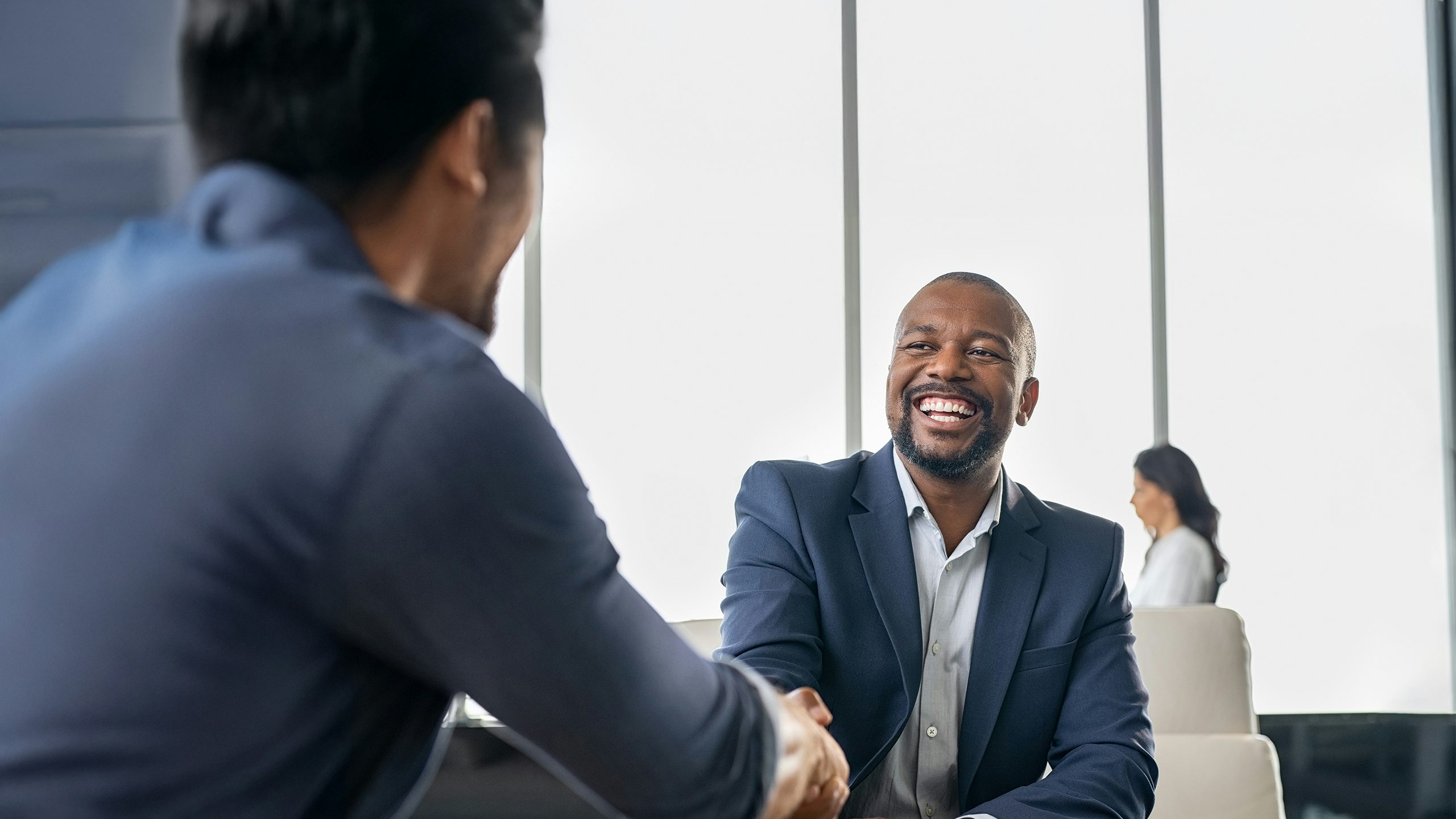 Two men shaking hands and smiling.