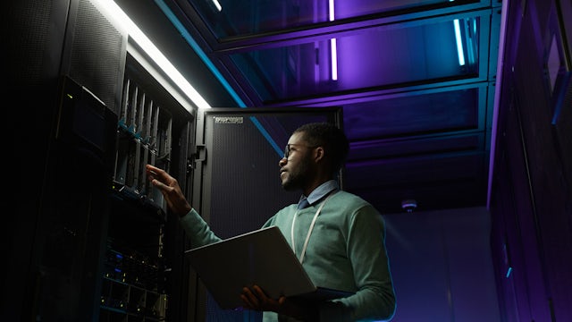 Man attends to serve rack holding a laptop.