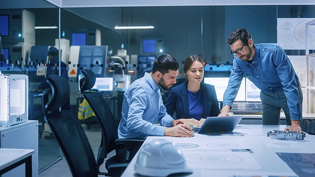 Engineers sitting around a laptop having a meeting in an office.