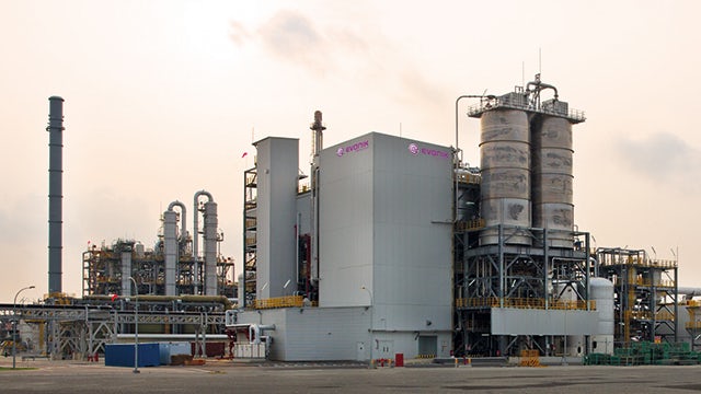 A photo of a methionine plant facility with a large industrial building and machinery in the background.