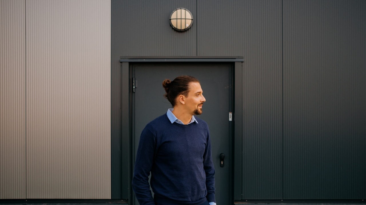 A man in a factory wearing a Siemens shirt is standing in front of a machine.