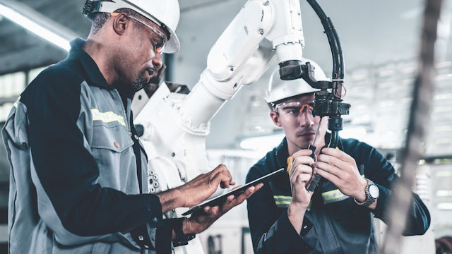 A person is standing in front of a large window with a view of a city skyline at night.