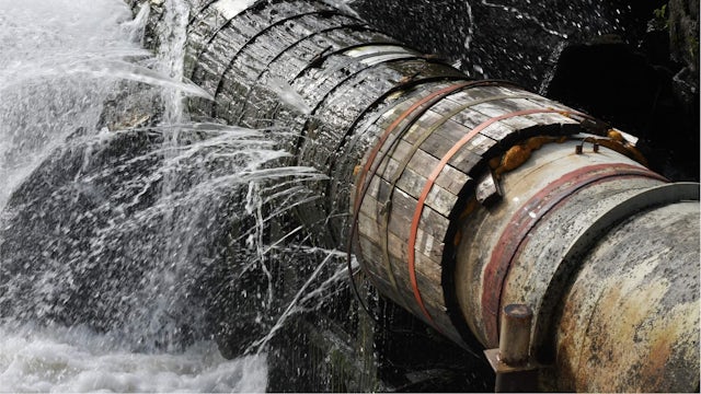 An action shot of water bursting out of a large pipe.