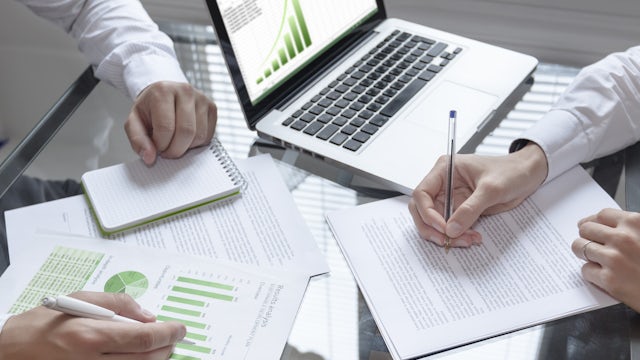 Person working on laptop with financial charts and graphs on screen