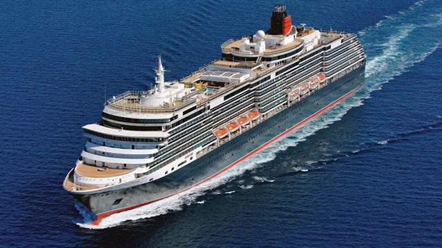 A person is standing on a boat, holding a rope, and looking at the sea.