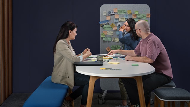 A person is sitting on a chair and appears to be working on a laptop.