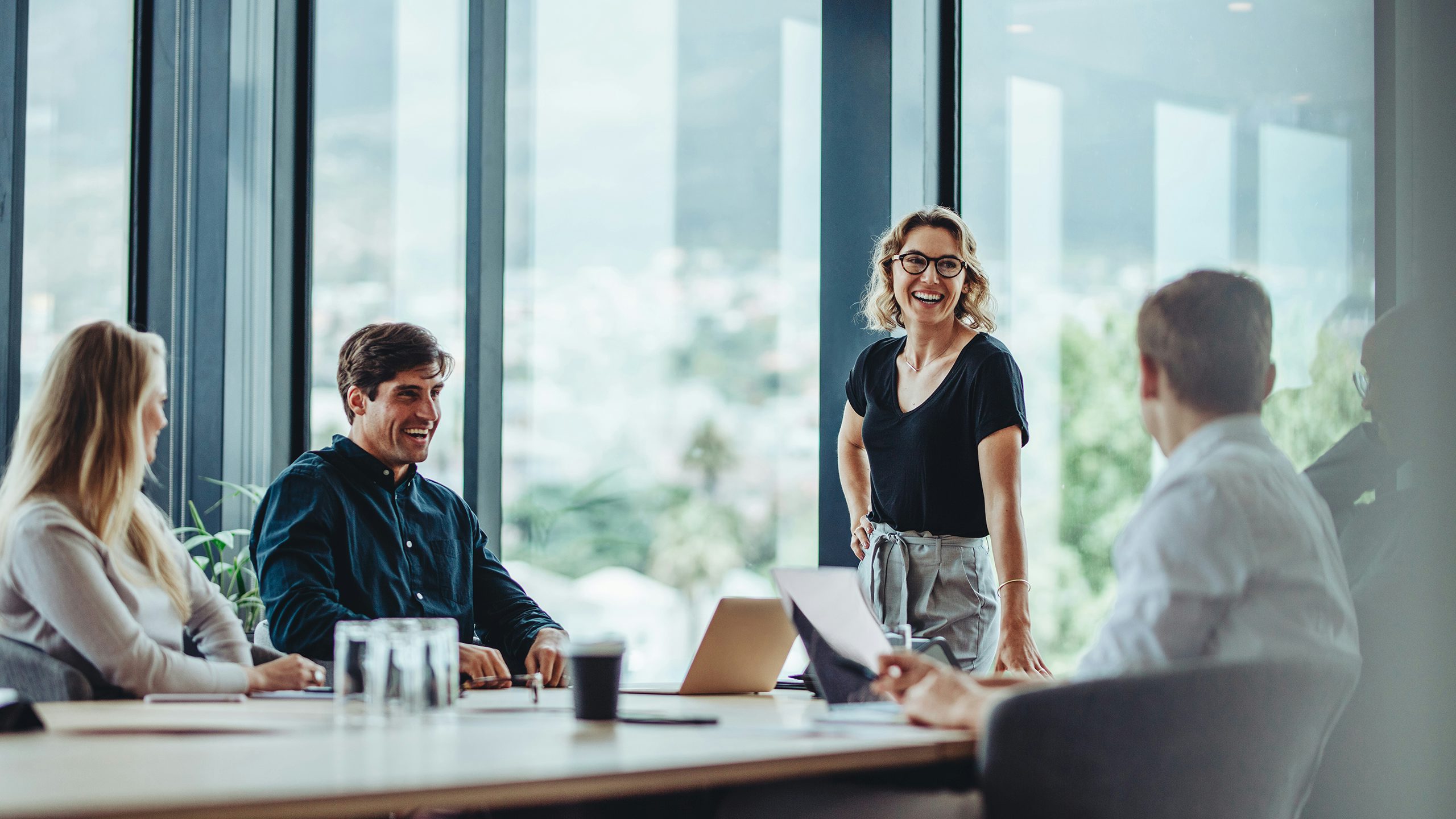 A person is standing in front of a large screen displaying a colorful abstract design.