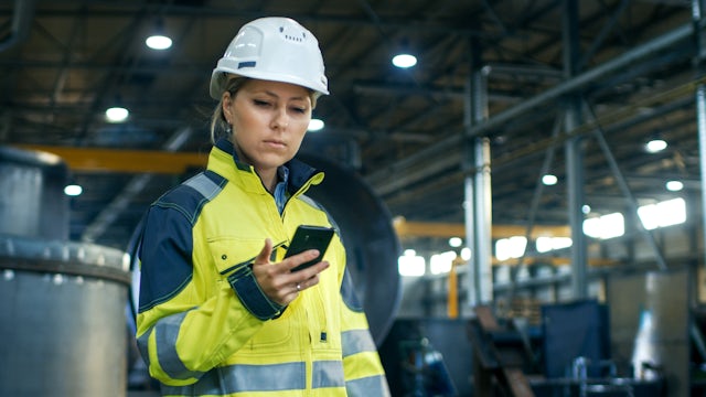 Industrial worker using smartphone in factory setting