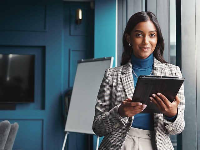 Woman smiling and holding a tablet.