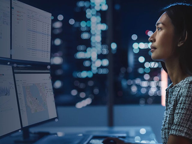 Woman looking at several monitors.