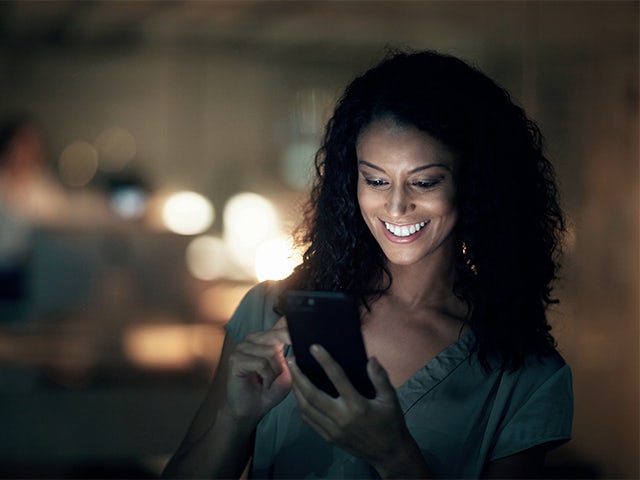 Woman smiling and looking at a mobile device.