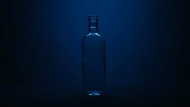 Glass bottle with blue lighting behind it.