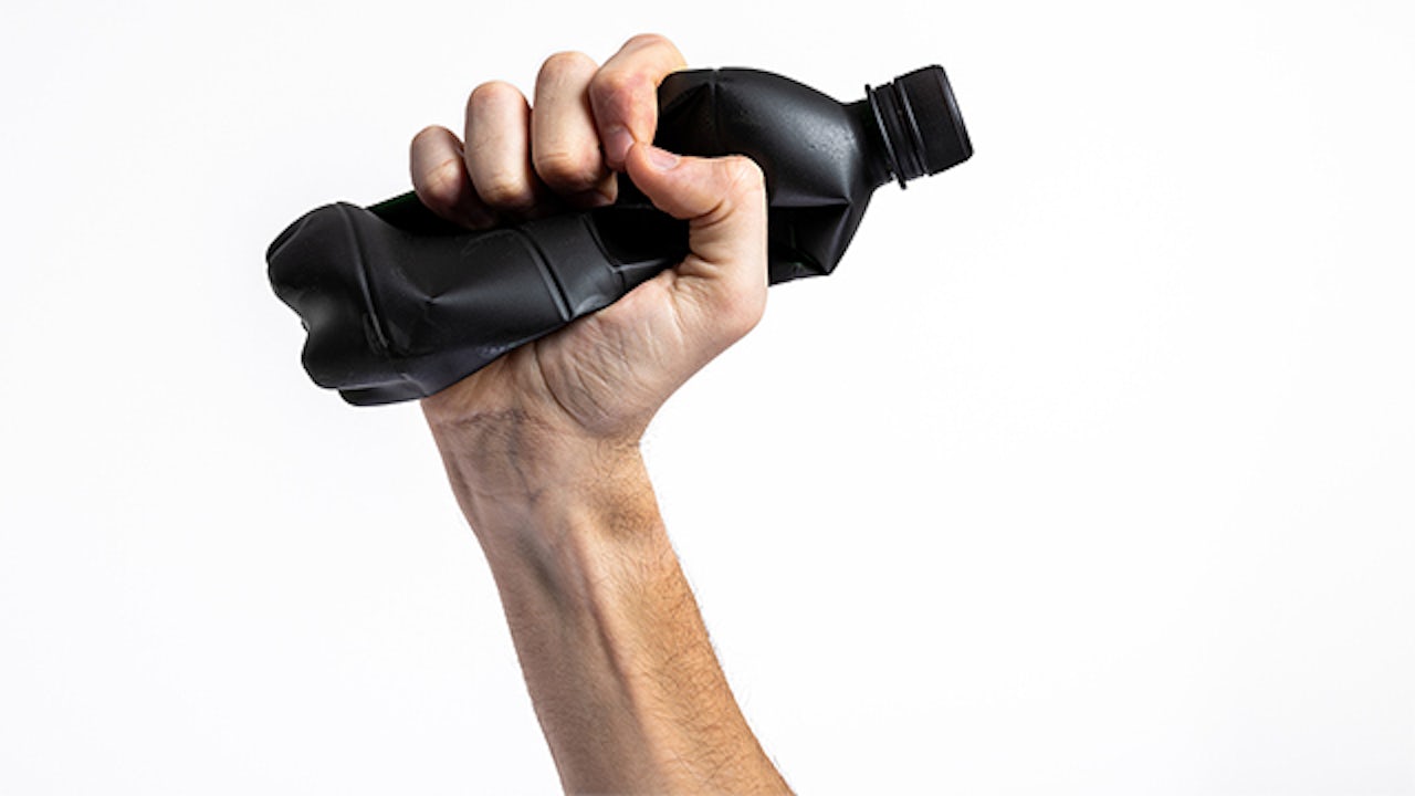 A hand holding a soda bottle with a label.