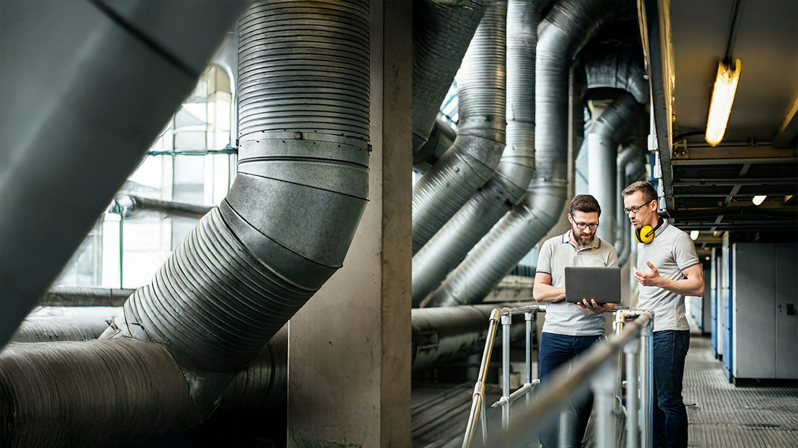 Woman in protective gear and mask standing in a laboratory setting with scientific equipment.