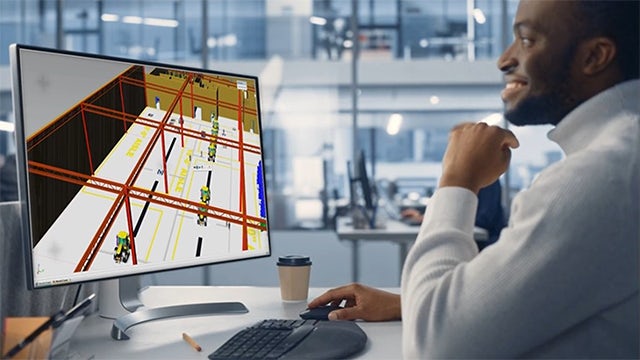Man working in office at a screen showing construction diagrams.