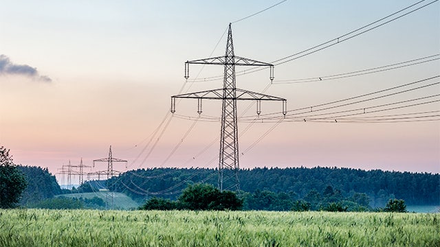 High-voltage transmission lines and towers against a cloudy sky