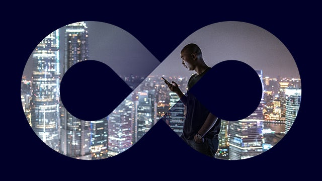 A night skyline with a prominent building in the foreground and a city skyline in the background.