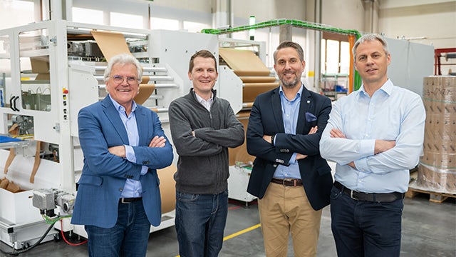 Four Hugo Beck leaders standing in front of machinery on the factory floor.