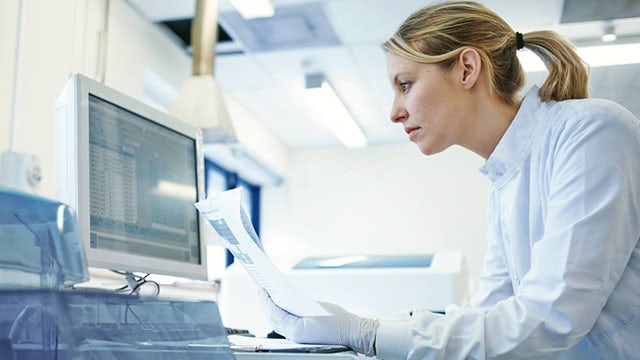 Woman in white lab coat working on a computer
