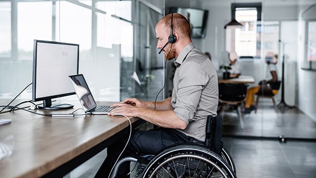 A person in a blue shirt is standing in front of a whiteboard with a diagram on it.