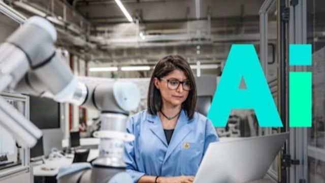 A woman in a blue lab jacket stands behind an industrial robot looking at a laptop.