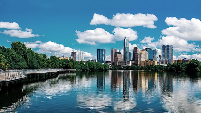 Skyline buildings reflected in river, vibrant urban scene.