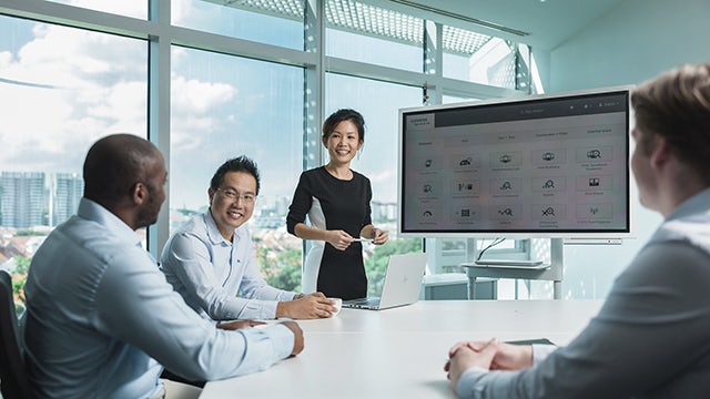 Office presentation on Siemens Railigent X digital solutions with colleagues engaged in discussion.