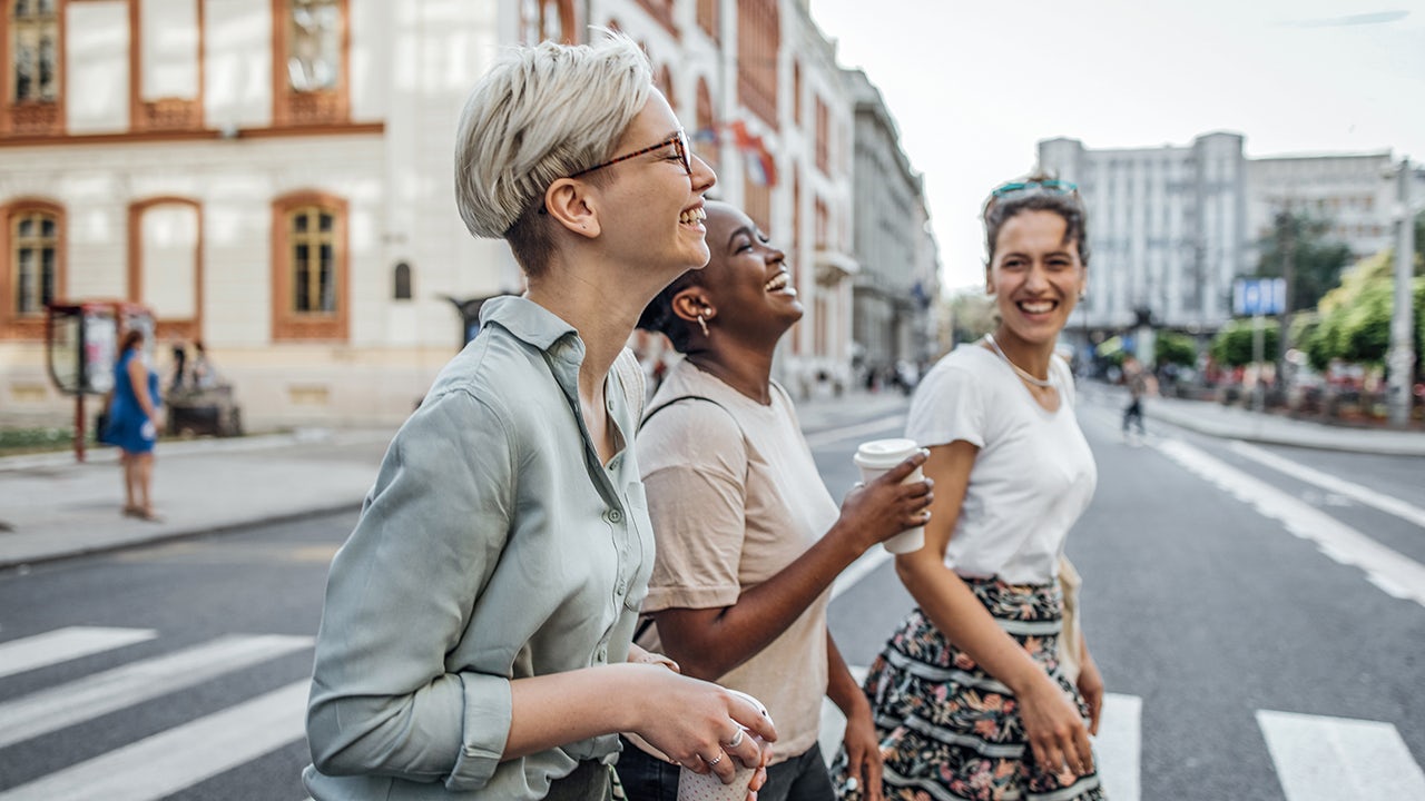 Sunlit city street with modern buildings and public transport, bustling urban environment.