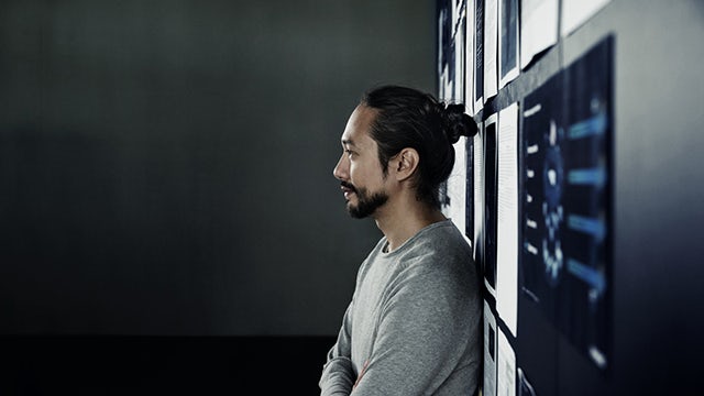 People collaborating around a large touchscreen display showing architectural plans and 3D models