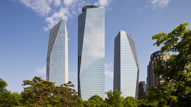 A modern office building with a glass facade under a clear blue sky.