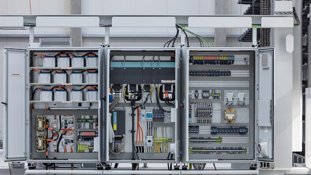 A warehouse with storage retrieval machines and a person operating one of them.